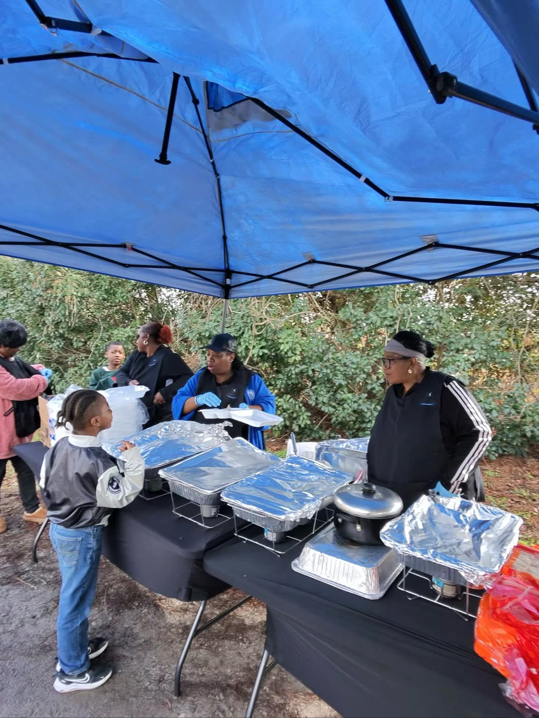 Volunteers serving hot food under the Givebacks tent